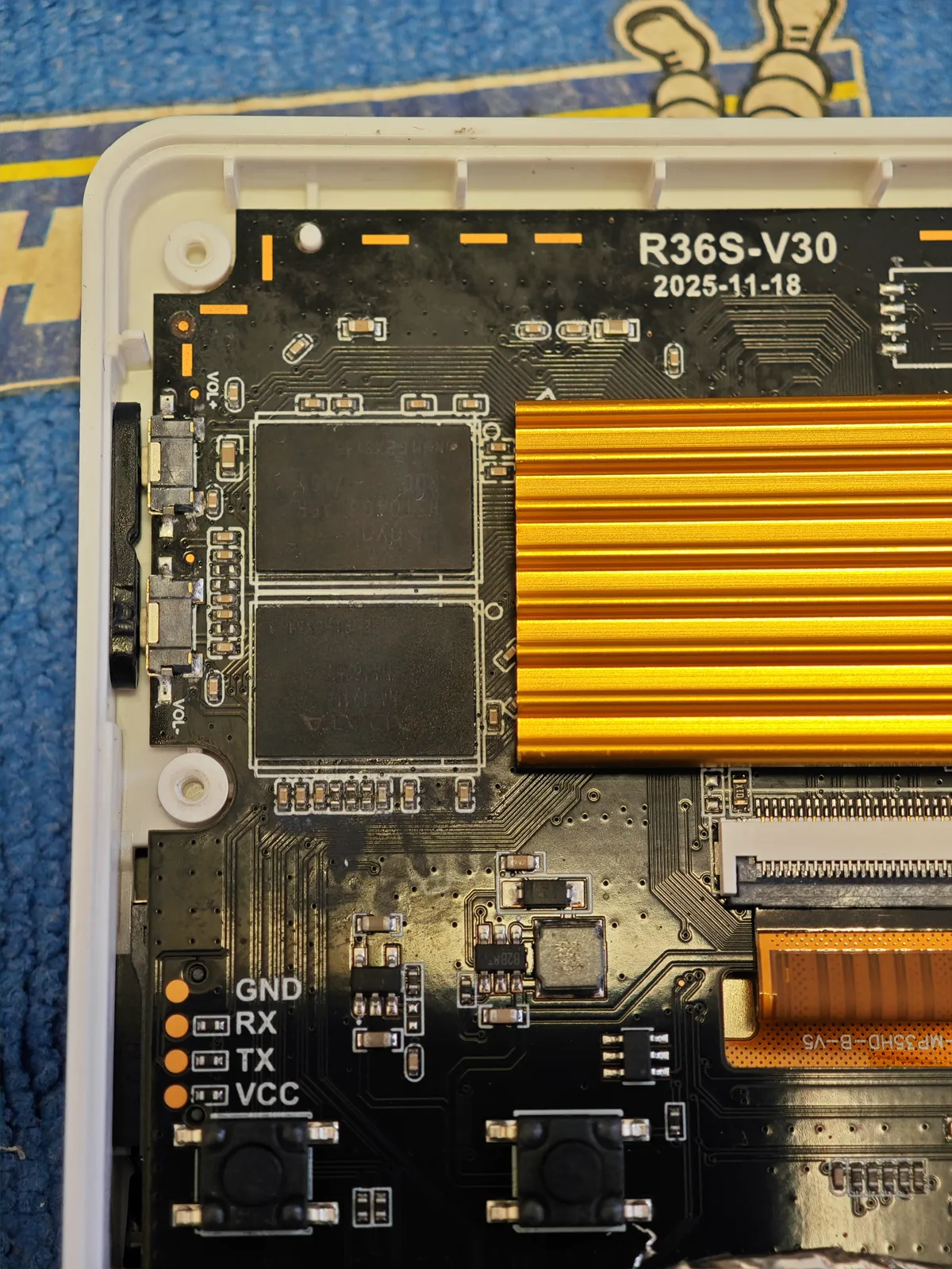 Two memory packages, closer in. The same V30 board, framed on the two packages and the gold heat spreader beside them, with the R36S-V30 marking and its date in the top right of the frame. This is the photograph that shows two packages, and that is all it shows. One frame of two packages is not a measurement of how much memory the board carries, so this page prints no capacity next to it.